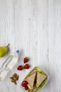 Healthy school lunch box with fresh organic vegetables sandwiches, walnuts, bottle of water and fruits on white wooden surface, to Royalty Free Stock Photo