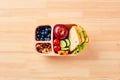 Healthy school lunch box with fruits, vegetables, sandwich, nuts on wooden table. Kids lunchbox top view Royalty Free Stock Photo