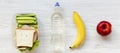 Healthy school lunch box with sandwich, fruits and bottle of water on a white wooden surface, overhead view. From above, top view Royalty Free Stock Photo