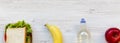 Healthy school lunch box with sandwich, fruits and bottle of water on white wooden surface, top view. From above, overhead. Royalty Free Stock Photo