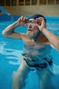 Healthy senior man swimming in indoor pool enjoying sportive lifestyle Royalty Free Stock Photo