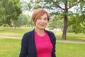 Healthy senior woman walking in park. Older woman with red short haircut outdoors. Mature beauty, 60s Royalty Free Stock Photo