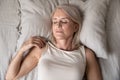 Healthy serene mature woman sleeping alone in bed, top view