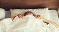 Healthy sleep, woman lying in bed under white blanket or duvet hiding her face in bedroom at home Royalty Free Stock Photo