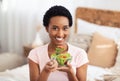 Healthy slimming diet concept. Cheerful black lady with tasty vegetable salad looking at camera and smiling at home