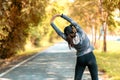 Healthy smiling woman warming up stretching her arms and looking away in the road outdoor. Asian runner woman workout before fitne Royalty Free Stock Photo