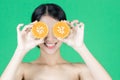 Healthy smiling young Asian woman holding fresh oranges over green isolated background. Wellness and beauty skin care concept Royalty Free Stock Photo