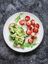 Healthy snack, breakfast - sandwich with avocado and fresh strawberries on a dark background, top view Royalty Free Stock Photo