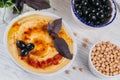 Healthy snack from crisp bread with hummus, olive oil, black olives and paprika on a white wooden background