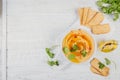 Healthy snack from crispbread with hummus, olive oil and cillantro on white wooden background