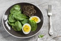 Healthy snack - fresh spinach and an egg on a brown plate