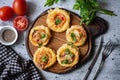 Healthy snack: mini pizza with cheese, tomatoes, fresh herbs and salami on a wooden board on a gray background. View Royalty Free Stock Photo