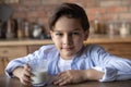 Headshot portrait of adorable preteen schoolboy drinking milk at kitchen