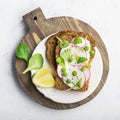 Healthy snack: slice grain bread with ricotta, green peas, radishes, lemon zest and juice. Top view