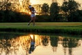 Healthy Sport. Asian Sporty woman golfer player chips and swing golf on the green sunset evening time, she presumably does exercis