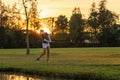 Healthy Sport. Asian Sporty woman golfer player chips and swing golf on the green sunset evening time, she presumably does exercis Royalty Free Stock Photo