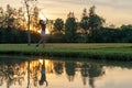 Healthy Sport. Asian Sporty woman golfer player chips and swing golf on the green sunset evening time, she presumably does exercis