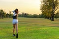 Healthy Sport. Asian Sporty woman golfer player doing golf swing tee off on the green evening time, Royalty Free Stock Photo