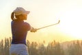 Healthy Sport. Asian Sporty woman golfer player doing golf swing tee off on the green evening time, she presumably does exercise.