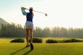 Healthy Sport. Asian Sporty woman golfer player doing golf swing tee off on the green evening time, she presumably does exercise. Royalty Free Stock Photo