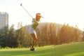 Healthy Sport. Asian Sporty woman golfer player doing golf swing tee off on the green, people presumably does exercise. Royalty Free Stock Photo