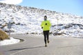 Healthy sport man running on road at snow mountains in trail runner hard workout in winter Royalty Free Stock Photo