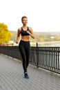 Healthy sportswoman running on sidewalk in the park in sunny day