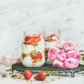 Healthy spring breakfast jars with pink raninkulus flowers, square crop