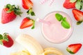 Healthy strawberry banana smoothie, top view table scene over white marble