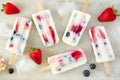 Summer strawberry blueberry yogurt popsicles, top view scattered on marble