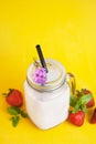 Healthy strawberry smoothie or drink yogurt in a mason a jar glass with berries and mint, over yellow background with copy space. Royalty Free Stock Photo