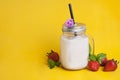 Healthy strawberry smoothie or drink yogurt in a mason a jar glass with berries and mint, over yellow background with copy space. Royalty Free Stock Photo