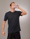 Healthy, studio or man drinking water for fitness, hydration or workout break isolated on grey background. Tired person Royalty Free Stock Photo