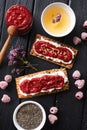 Healthy sugar free dessert and herbal tea. Raspberry chia jam on crispy bread and cream cheese with frozen berries on black Royalty Free Stock Photo