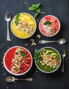 Healthy summer breakfast concept. Colorful fruit smoothie bowls with nuts, oat granola and mint leaves on black Royalty Free Stock Photo