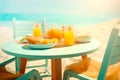 Healthy summer breakfast on seaside. Turquoise chairs and round table on sand beach near sea water. Summer holiday or vacation