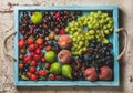 Healthy summer fruit variety. Black and green grapes, strawberries, figs, sweet cherries, peaches in blue wooden tray