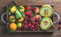 Healthy summer fruit variety. Melon, sweet cherries, peach, strawberry, orange and lemon in wooden tray over rustic Royalty Free Stock Photo