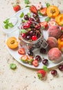 Healthy summer fruit variety. Sweet cherries in glass jar, strawberries, peaches, apricots and mint leaves on white Royalty Free Stock Photo