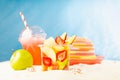 Healthy summer picnic on tropical beach with takeaway fresh food - fruit salad, cold strawberry cocktail, green apple, sun hat. Royalty Free Stock Photo