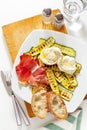 healthy summer salad with grilled zucchini, mozzarella and prosciutto. Fresh sliced bread ciabatta. On white. Royalty Free Stock Photo