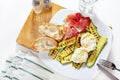 healthy summer salad with grilled zucchini, mozzarella and prosciutto. Fresh sliced bread ciabatta. On white. Royalty Free Stock Photo