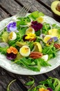 Healthy summer salad with quail eggs, avocado, pecans, wild rocket, red onion and edible viola flowers. Royalty Free Stock Photo