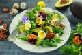 Healthy summer salad with quail eggs, avocado, pecans, wild rocket, red onion and edible viola flowers. Royalty Free Stock Photo