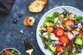 Healthy summer salad with strawberry, grilled chicken slices, fresh herbs with blueberries, avocado and walnuts, blue stone table