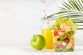 Healthy summer tropical take away food set of orange juice, green apple, salad with shrimps, lettuce, red bell pepper, croutons.