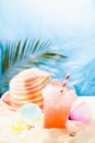 Healthy summer vacation and relax on tropical beach with beach plays, cold drink, fruit, sun hat under palm leaves with sun glare. Royalty Free Stock Photo