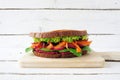 Healthy superfood sandwich with avocado, beet hummus, spinach radishes and carrots on a wooden board against white wood Royalty Free Stock Photo