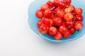 High angle view to ripe cherry berries with water droplets into blue plate on a white background Royalty Free Stock Photo