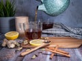 Healthy tea poured into transparent cup. Teapot, lemon, ginger, cardamom, heather bunch and glass jar Royalty Free Stock Photo